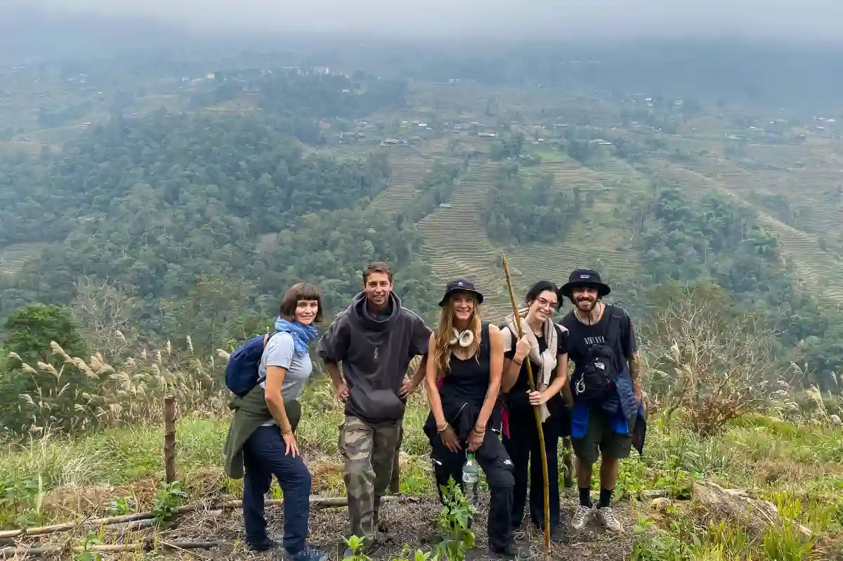 Group of trekkers on a misty mountain ridge above terraced valleys in Sapa